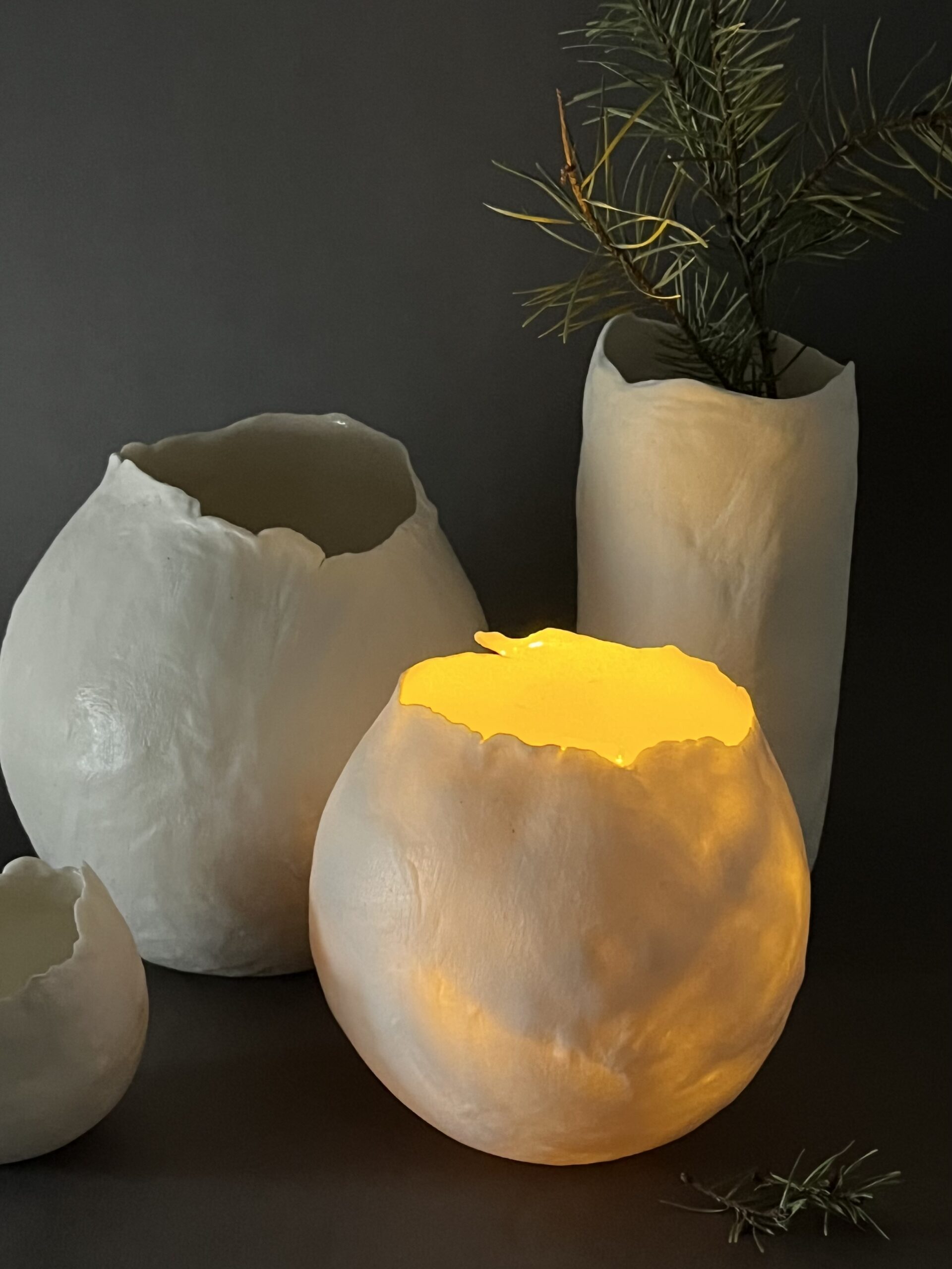 Photophores Éclosion en porcelaine papier, l'un allumé diffusant une lumière jaune chaude, branche de pin