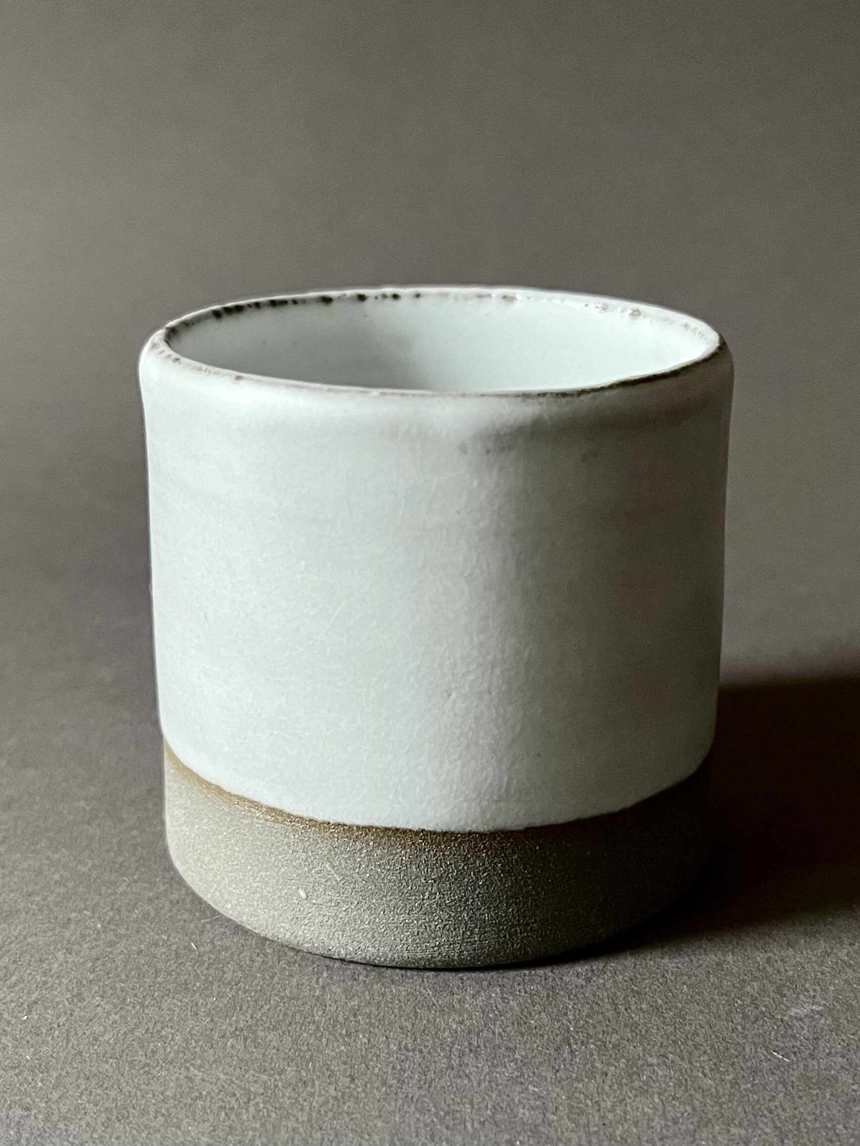 Gobelet Steph en grès gris à l'émail blanc, base brute grise, vue de face sur fond gris
