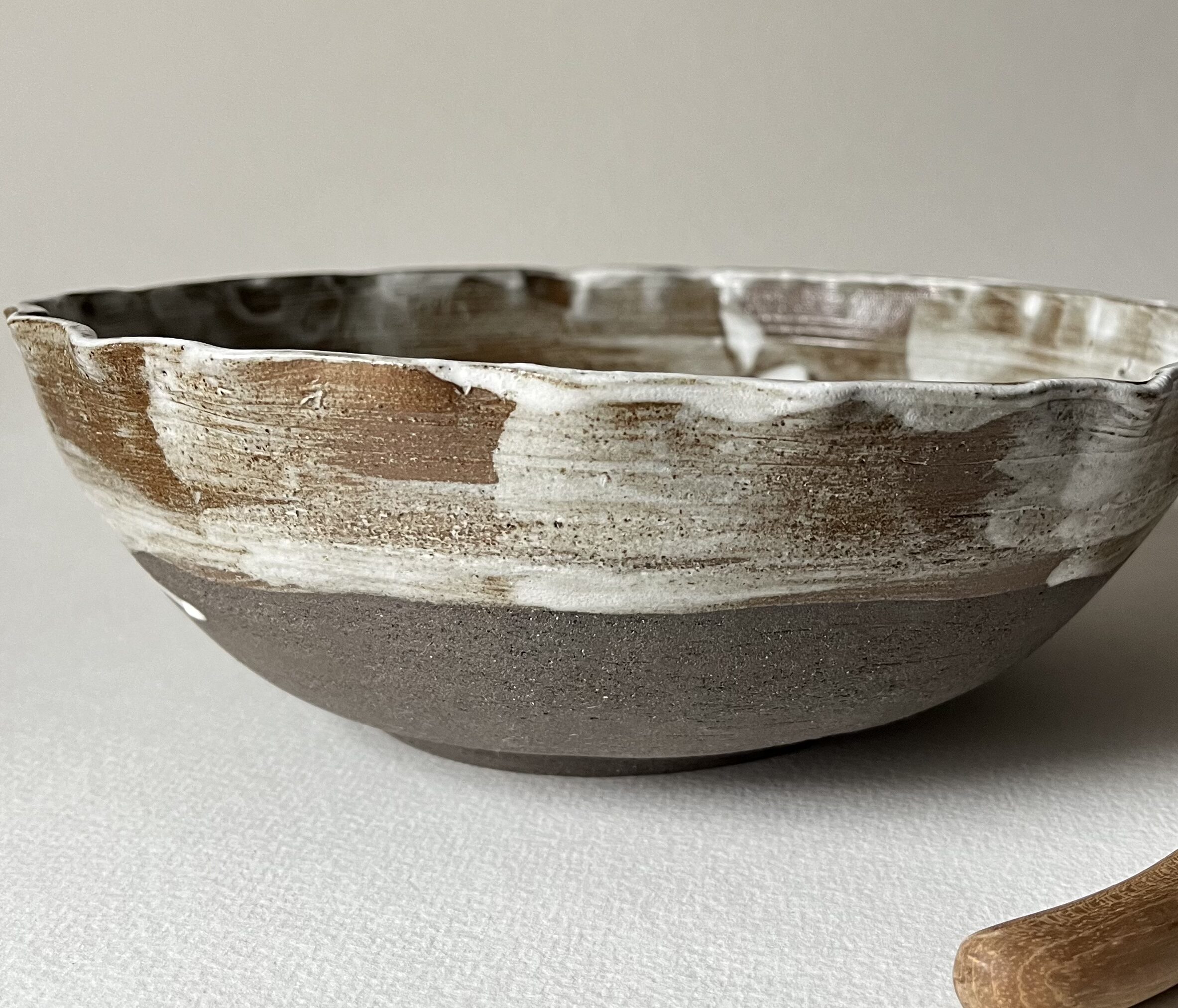 Saladier marbré marron et blanc de profil, bord irrégulier modelé, base en grès sombre brut