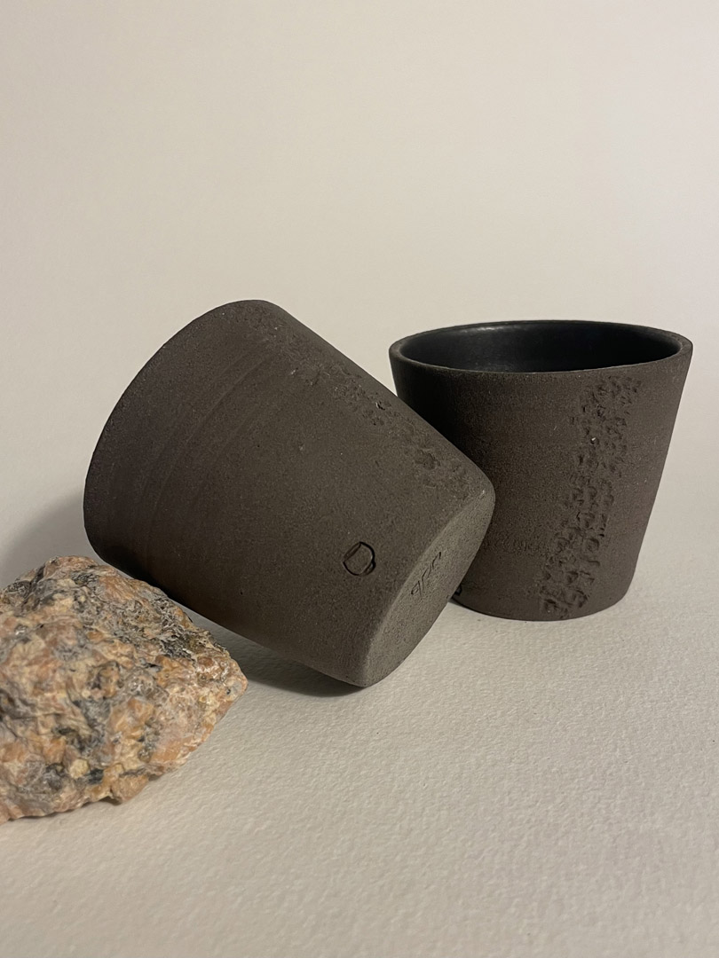 Gobelet Treb couché montrant son dessous tamponné adb, second gobelet debout et granit rose