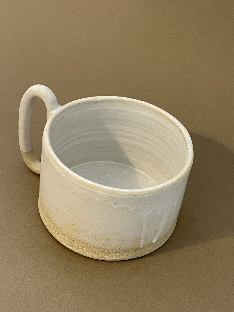 Tasse à thé Caro en grès chamotté émaillé blanc mat, vue de trois quarts, base brute