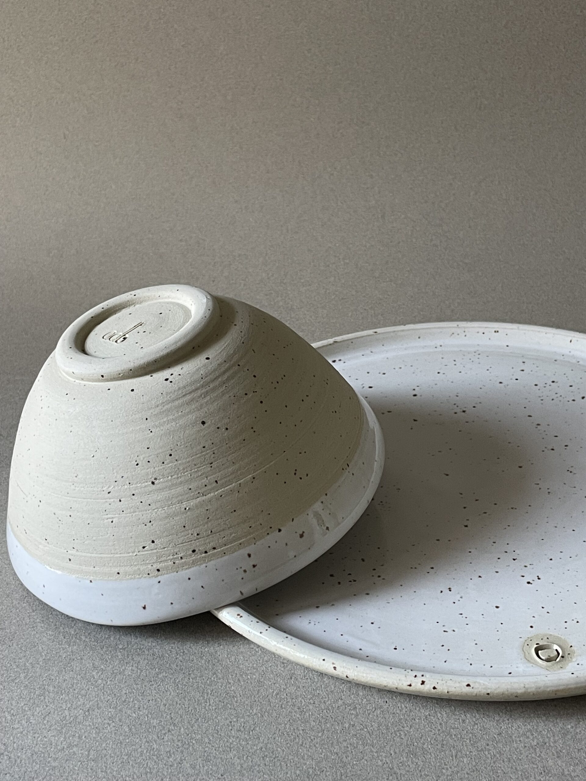 Bol Maya retourné montrant son pied en grès brut, posé sur une assiette plate Maya