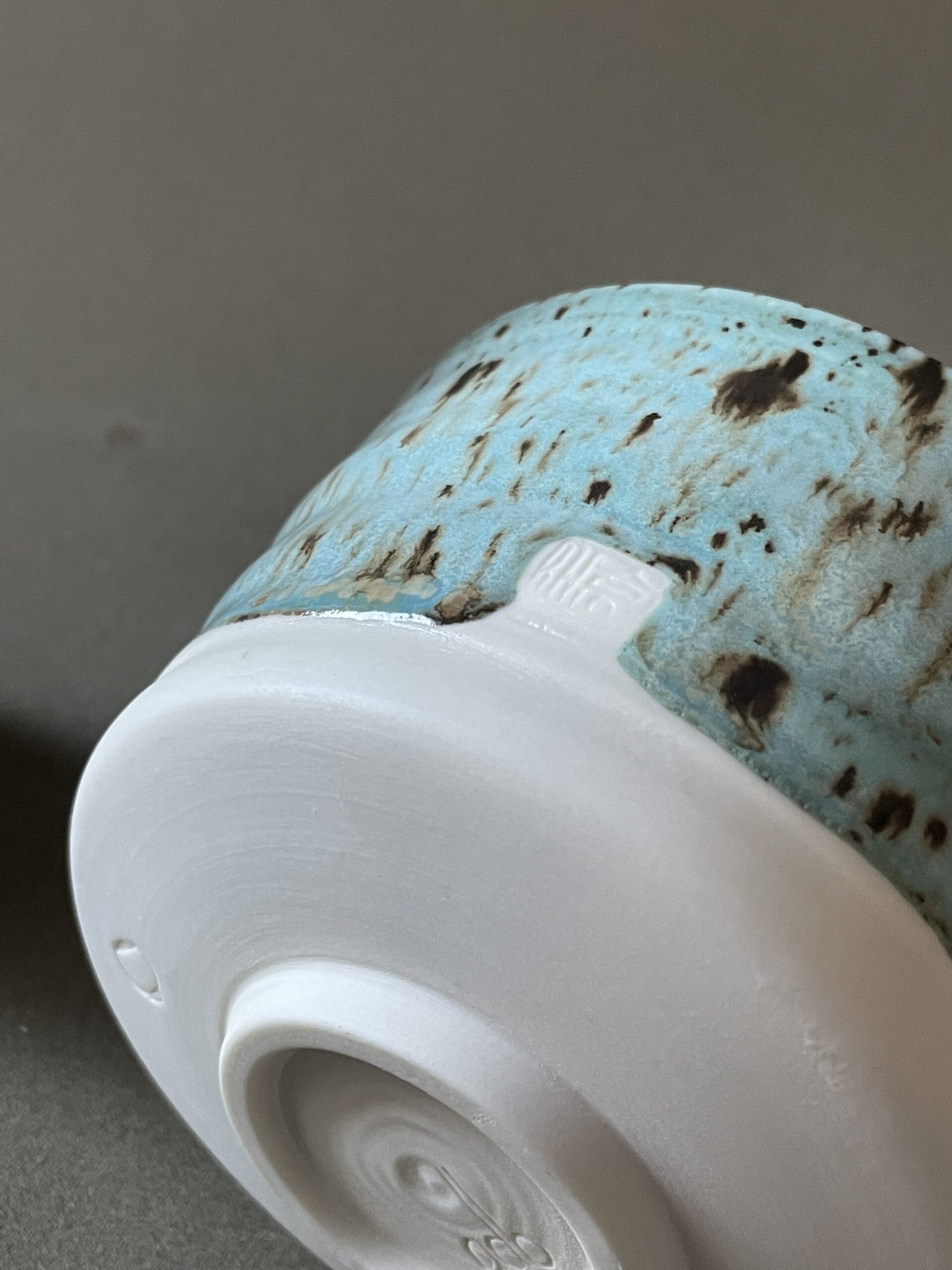 Gros plan sur le pied en porcelaine brute du bol à matcha Osaka et son hanko japonais, émail céladon tacheté