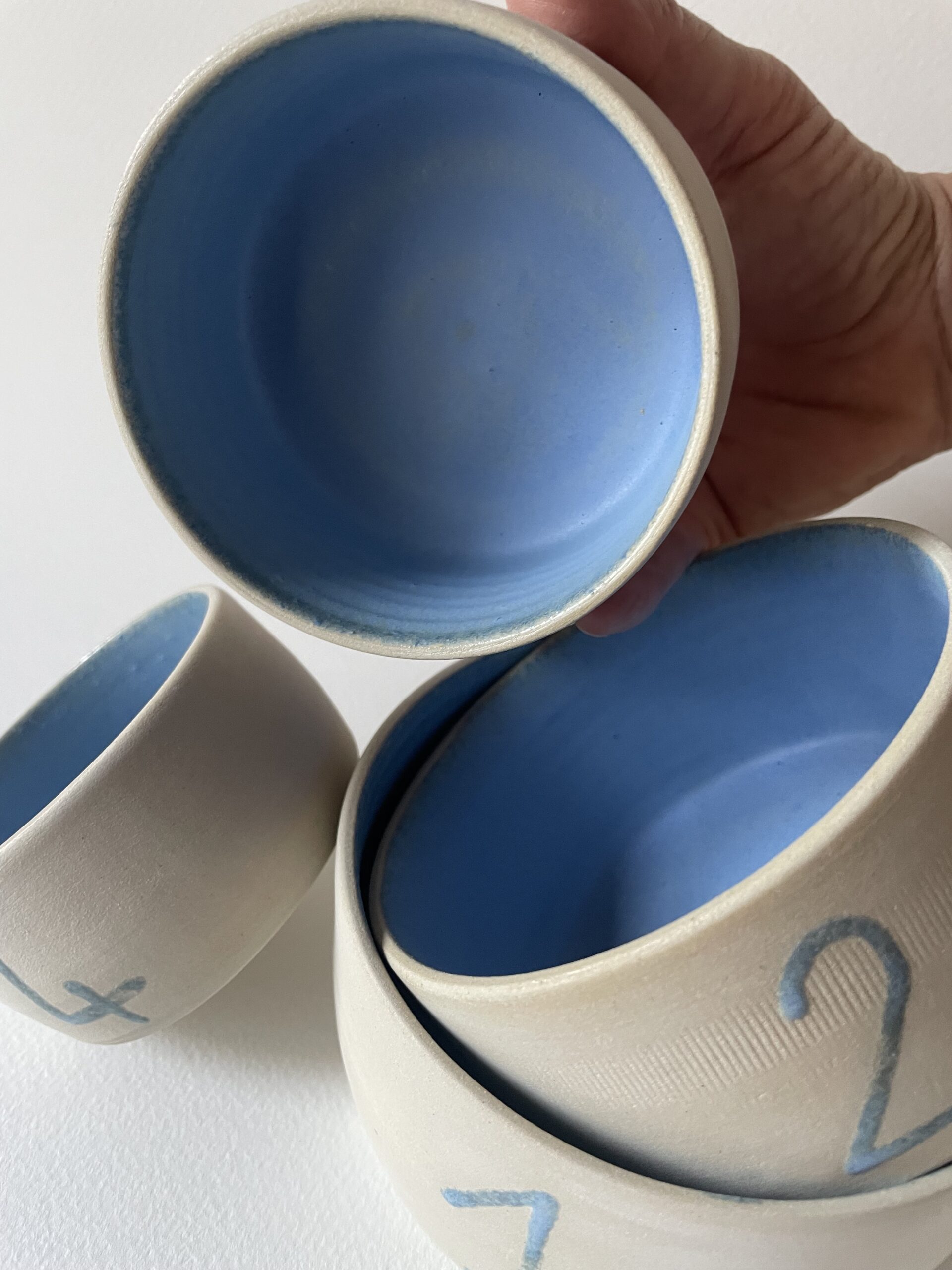 Bols gigognes en grès brut à l'intérieur émaillé bleu, tenus et empilés, numéros bleus