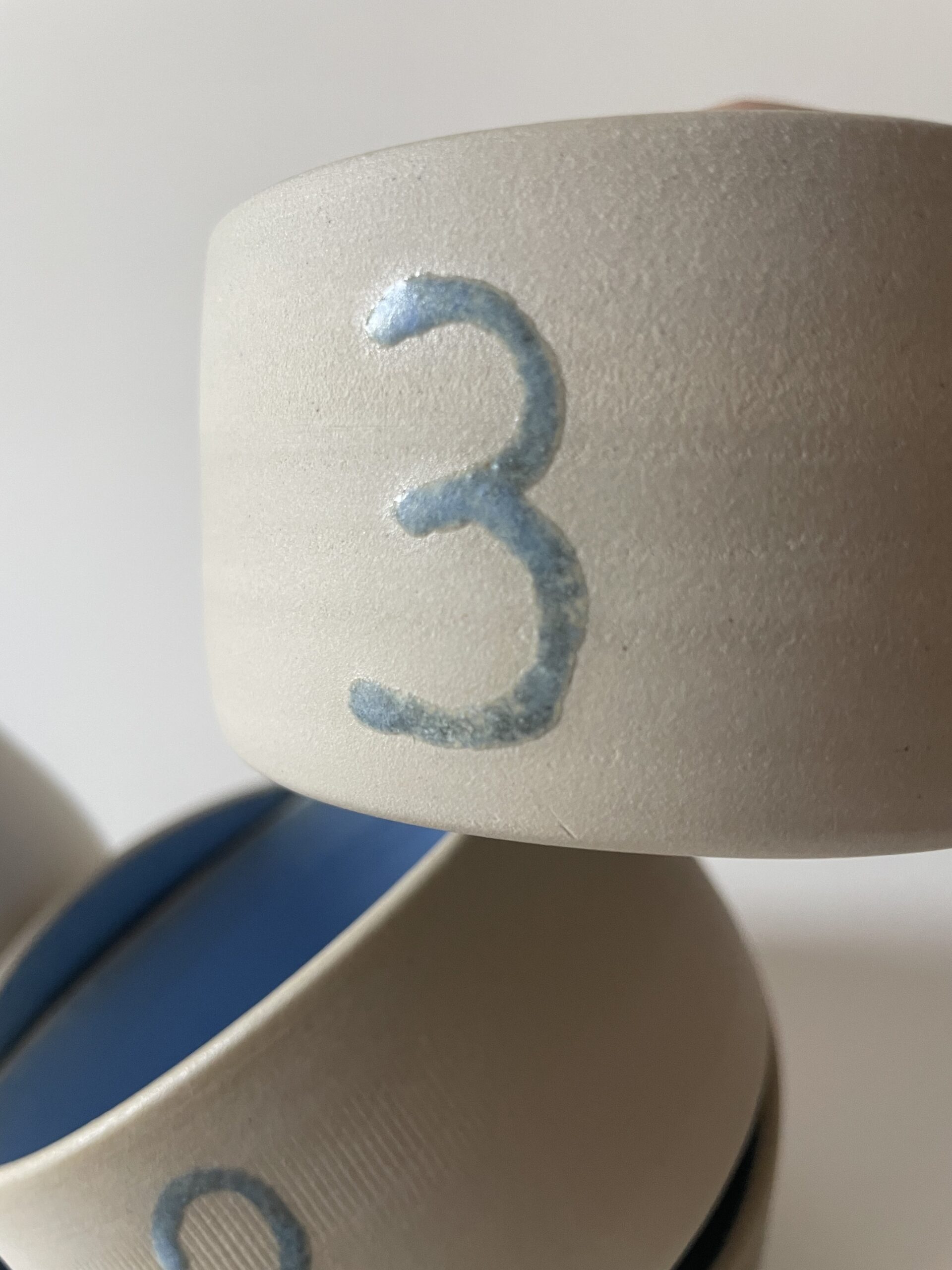 Gros plan sur le bol gigogne numéro 3 en grès brut, chiffre bleu et intérieur émaillé bleu