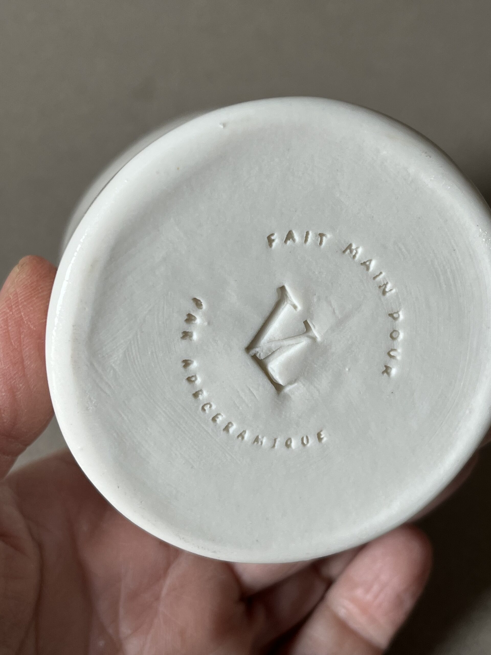 Dessous d'une saucière en porcelaine tenue en main, tampon « fait main pour Le Vieux Logis par adb Céramique »