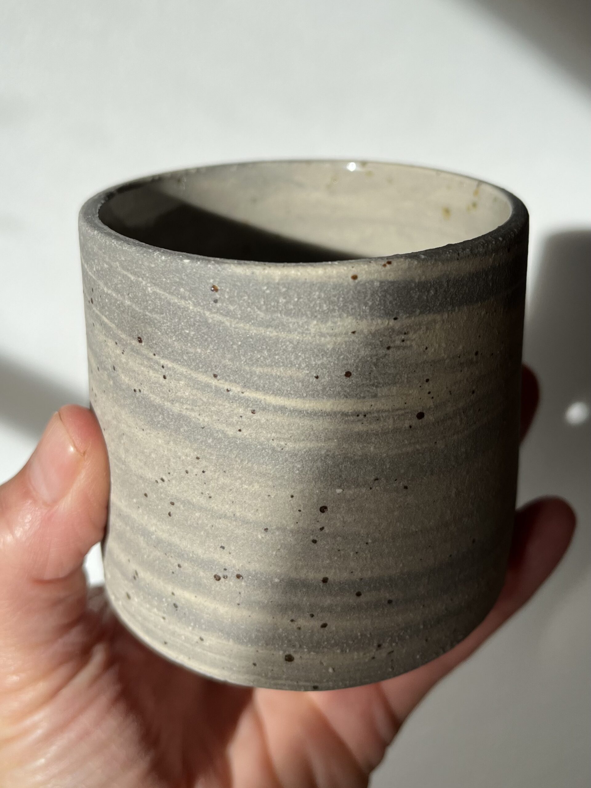 Gobelet Steph en grès gris marbré laissé brut à l'extérieur, tenu en main