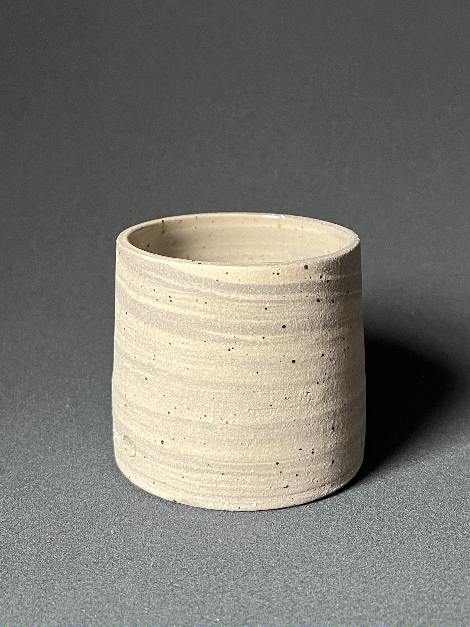 Gobelet Steph en grès gris marbré pyrité laissé brut, vue de face sur fond gris