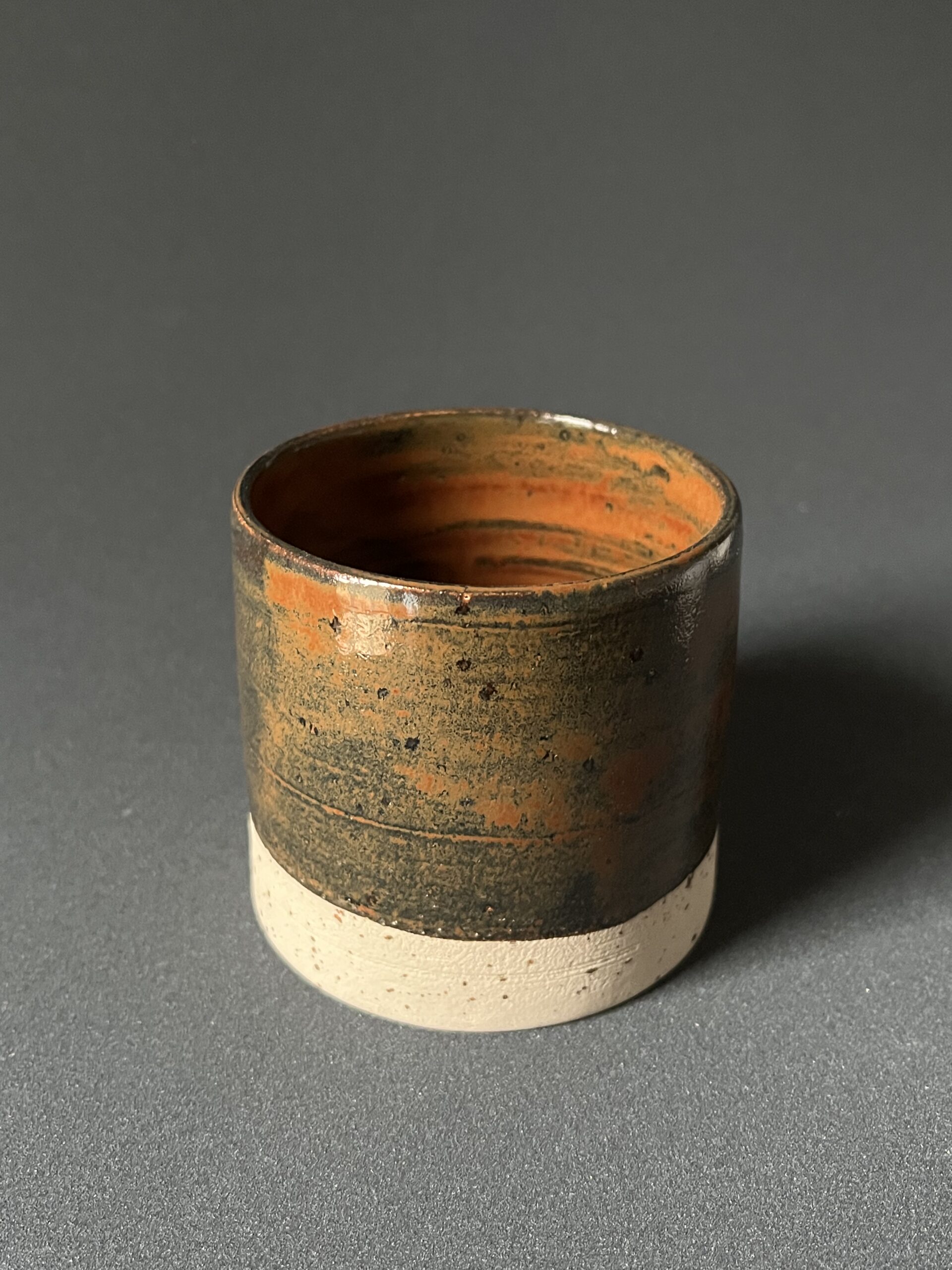 Gobelet Steph en grès à l'émail automne brillant orange et vert sombre, base brute, sur fond gris