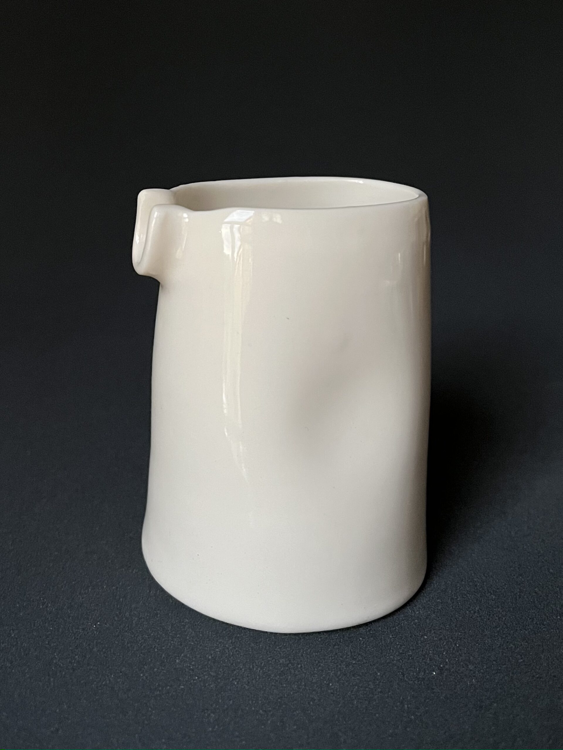 Grande saucière verseuse en porcelaine blanche brillante avec renfoncement latéral, sur fond sombre