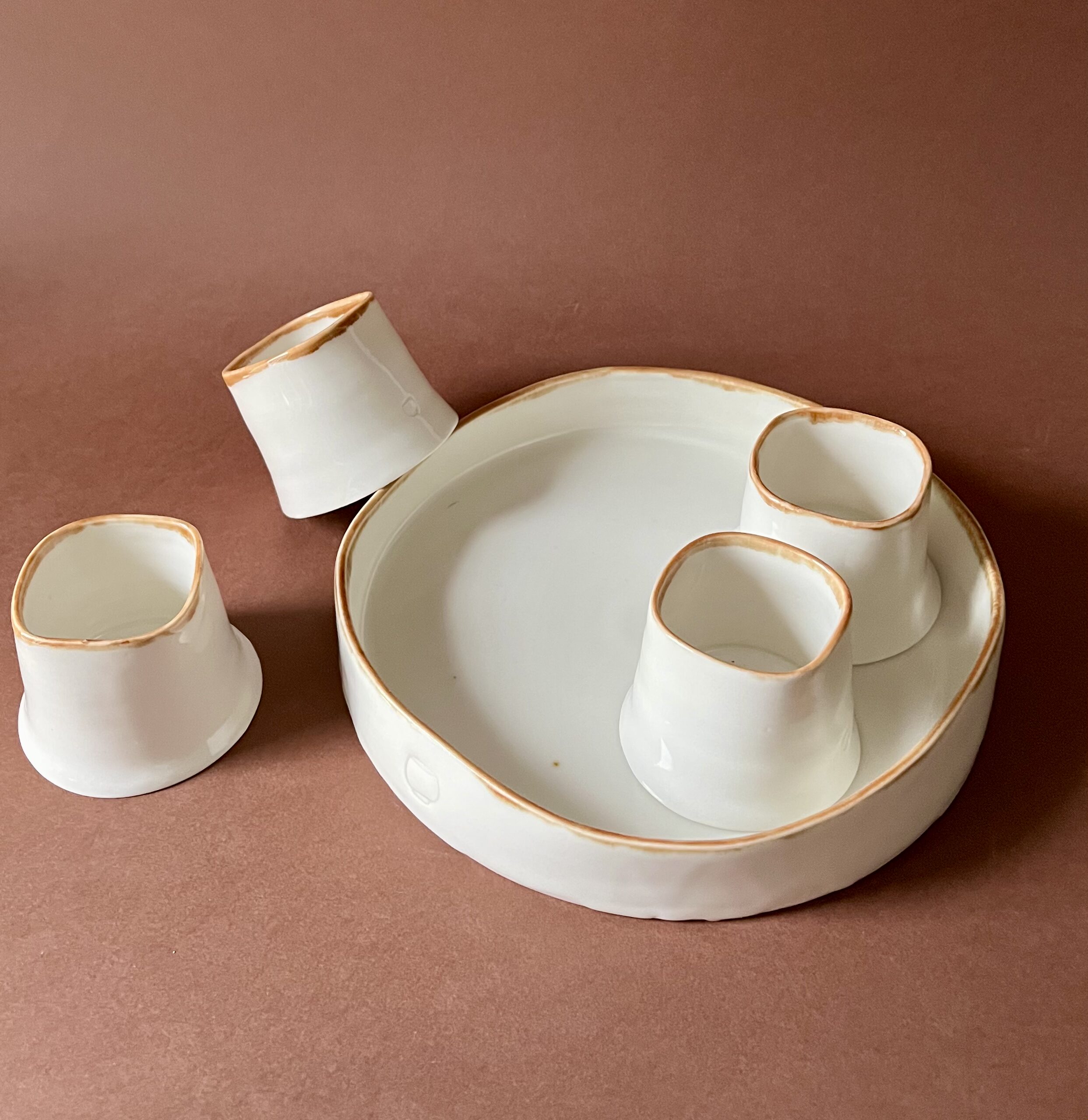 Set à café Ulysse liseré marron, tasses expresso posées dans et autour du plateau rond en porcelaine