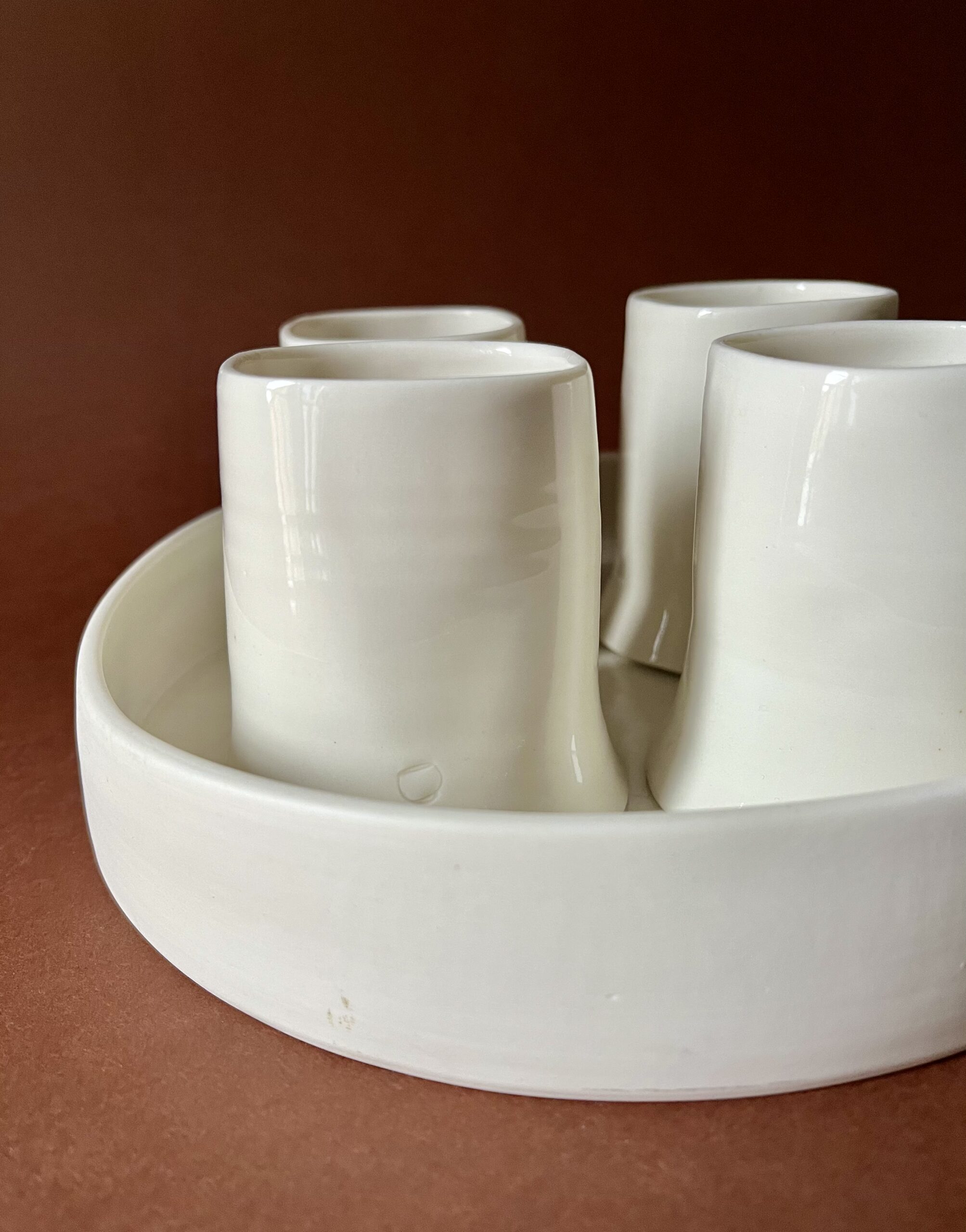 Gros plan sur les tasses Ulysse blanches en porcelaine calées dans leur plateau rond