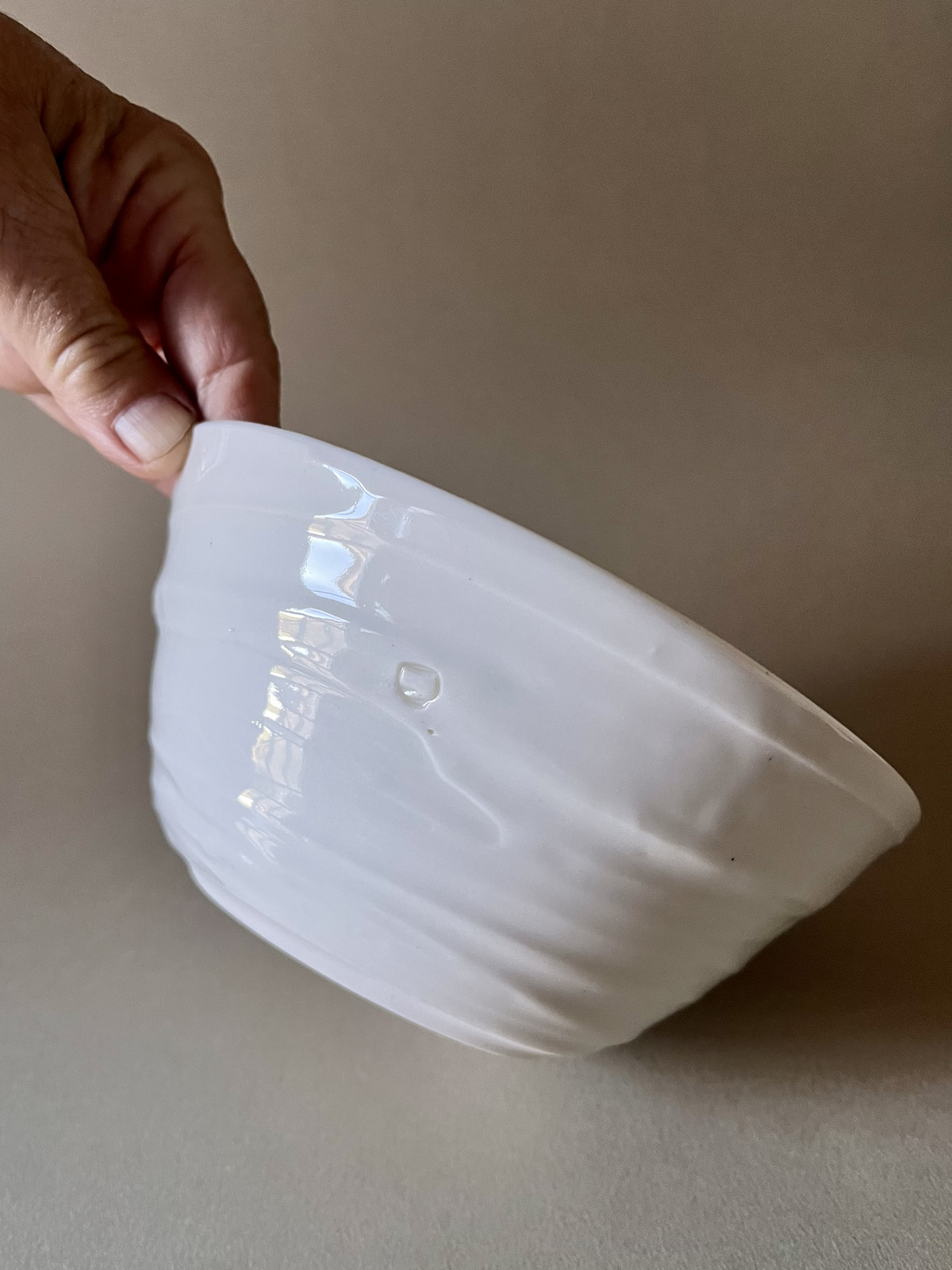 Bol Purete en porcelaine blanche tenu incliné, montrant sa paroi striée et son pied