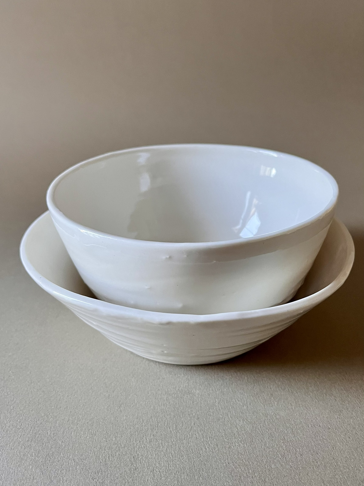 Deux bols Purete en porcelaine blanche emboîtés, vue de face sur fond beige