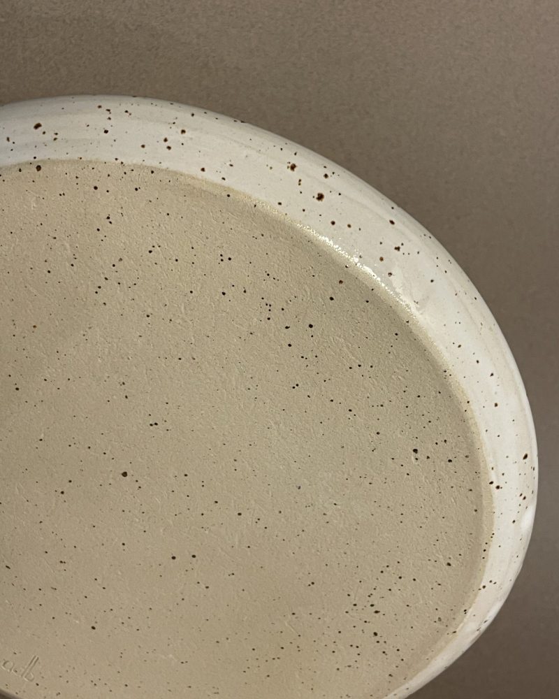 Dessous de l'assiette plate Maya, grès pyrité laissé brut et rebord émaillé blanc