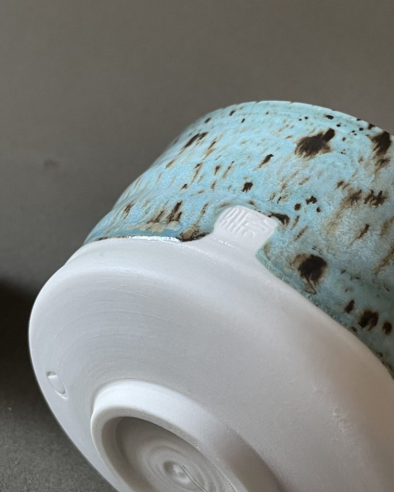 Gros plan sur le pied en porcelaine brute du bol à matcha Osaka et son hanko japonais, émail céladon tacheté