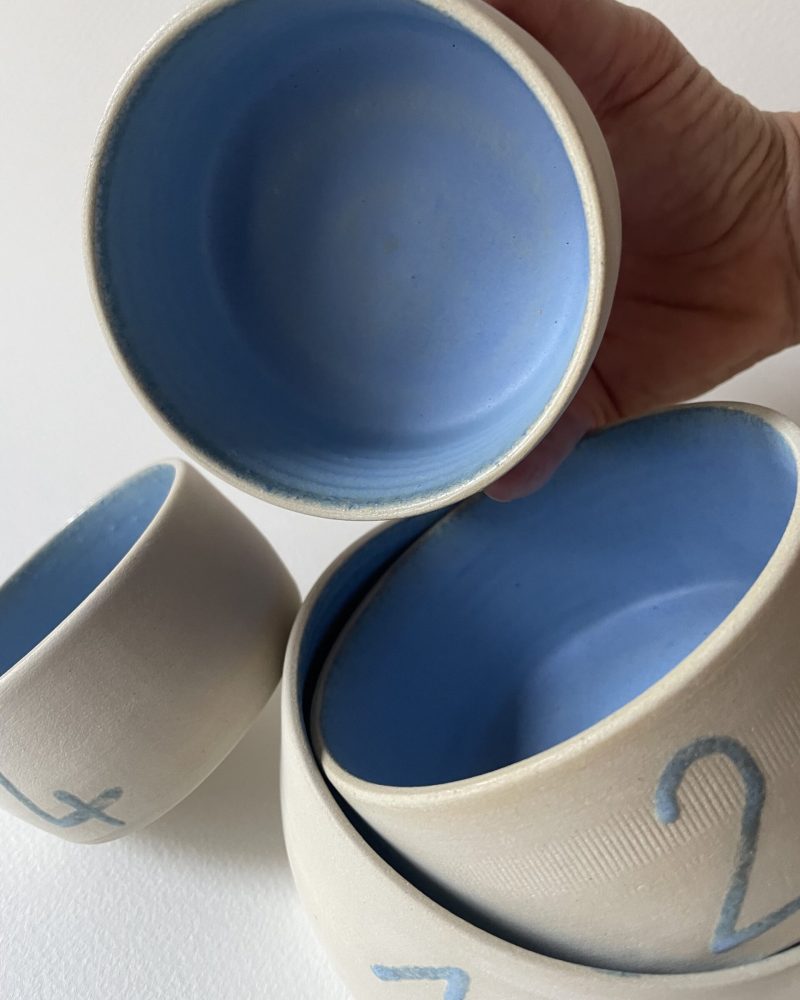 Bols gigognes en grès brut à l'intérieur émaillé bleu, tenus et empilés, numéros bleus