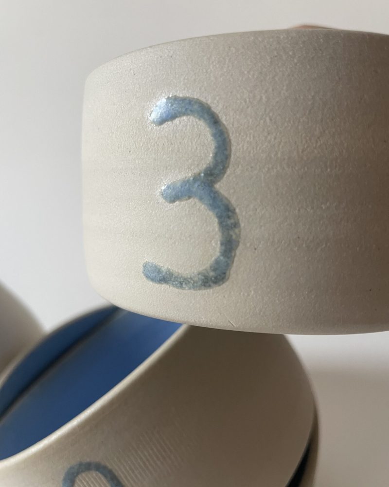 Gros plan sur le bol gigogne numéro 3 en grès brut, chiffre bleu et intérieur émaillé bleu