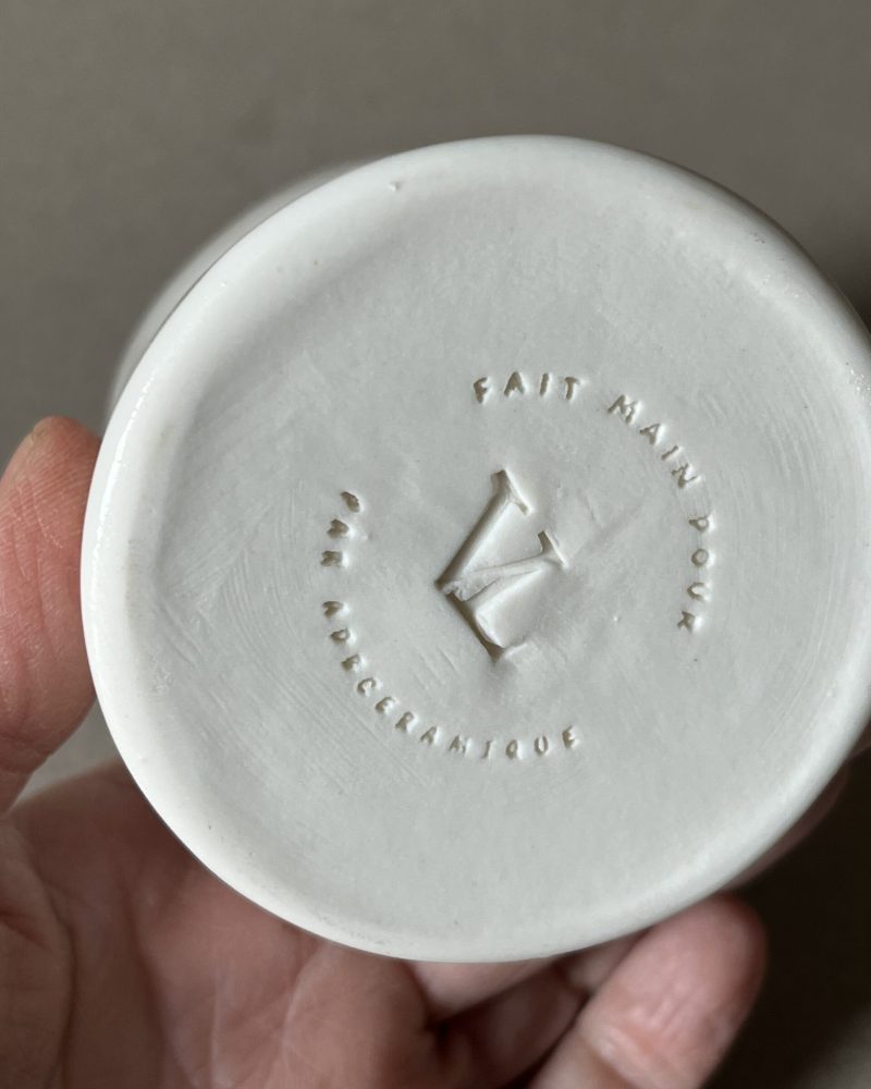 Dessous d'une saucière en porcelaine tenue en main, tampon « fait main pour Le Vieux Logis par adb Céramique »