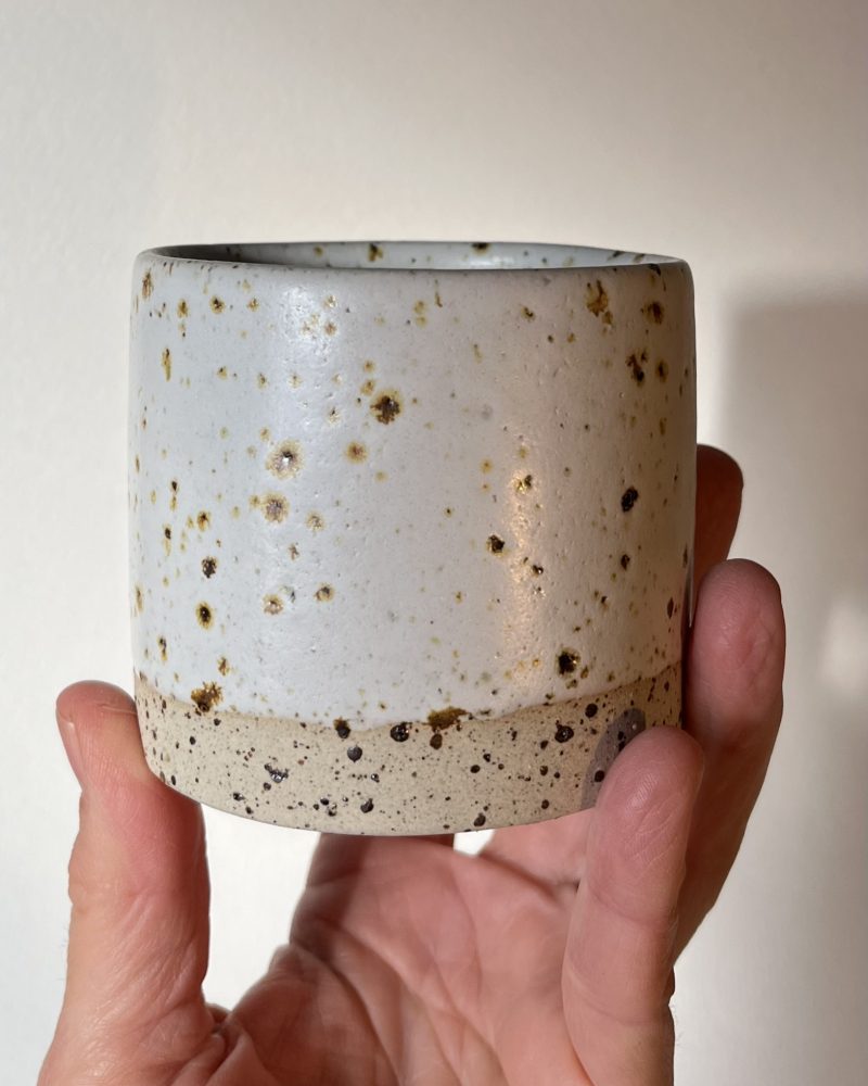 Gobelet Steph en grès pyrité à l'émail blanc brillant moucheté, tenu en main, base brute