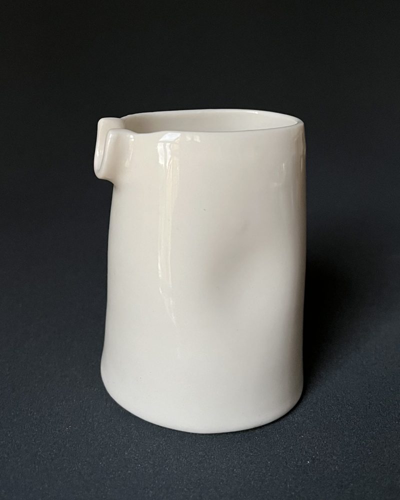 Grande saucière verseuse en porcelaine blanche brillante avec renfoncement latéral, sur fond sombre