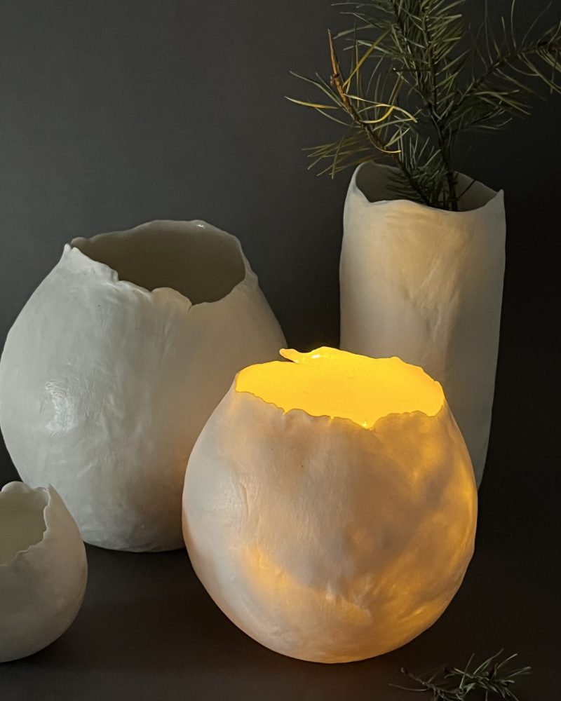 Photophores Éclosion en porcelaine papier, l'un allumé diffusant une lumière jaune chaude, branche de pin