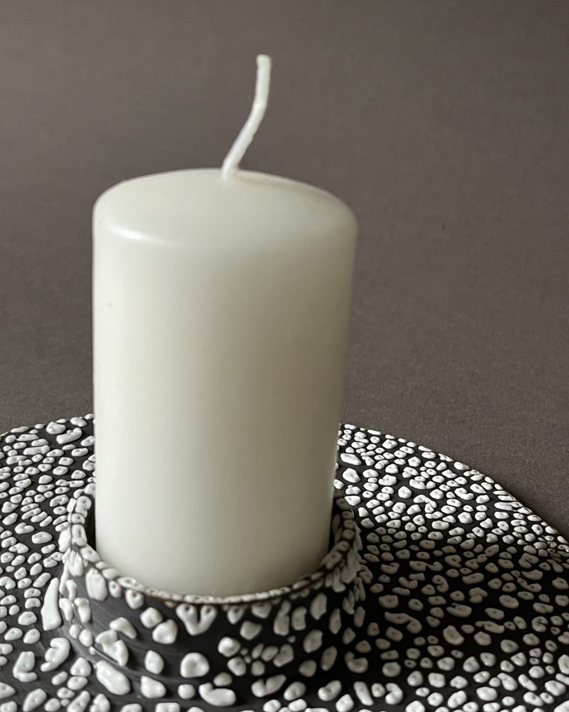 Bougie blanche cylindrique posée dans le bougeoir plat Winter, émail rétracté blanc en billes