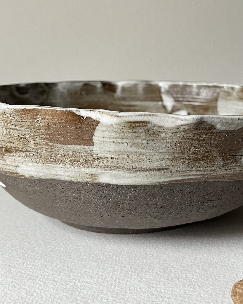 Saladier marbré marron et blanc de profil, bord irrégulier modelé, base en grès sombre brut