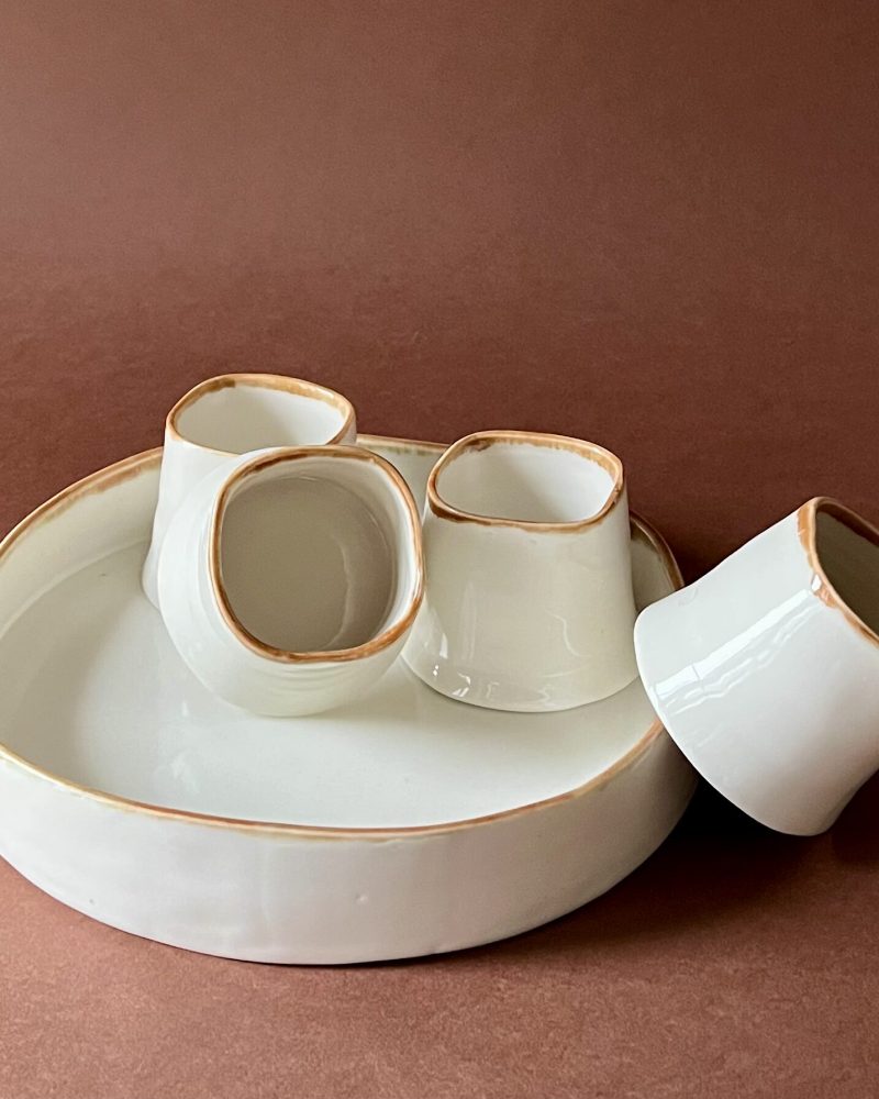 Set à café Ulysse en porcelaine blanche à liseré marron, tasses carrées sur plateau rond, l'une couchée