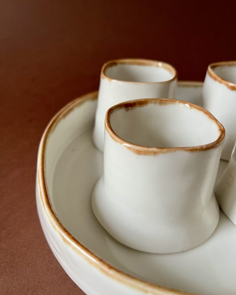 Gros plan sur les lèvres à liseré marron des tasses Ulysse en porcelaine blanche sur leur plateau