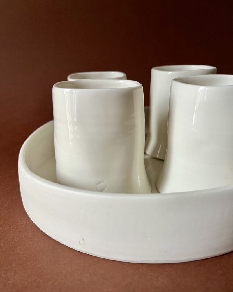 Gros plan sur les tasses Ulysse blanches en porcelaine calées dans leur plateau rond