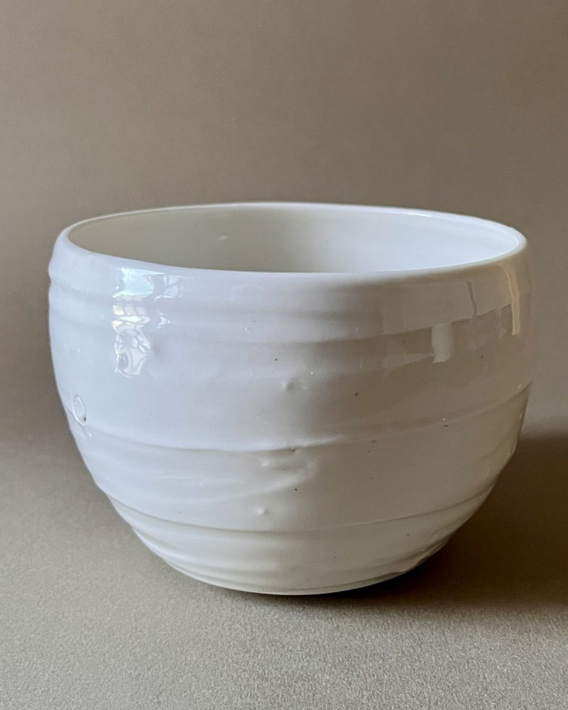 Bol Purete en porcelaine blanche brillante aux parois légèrement striées, vue de face sur fond beige