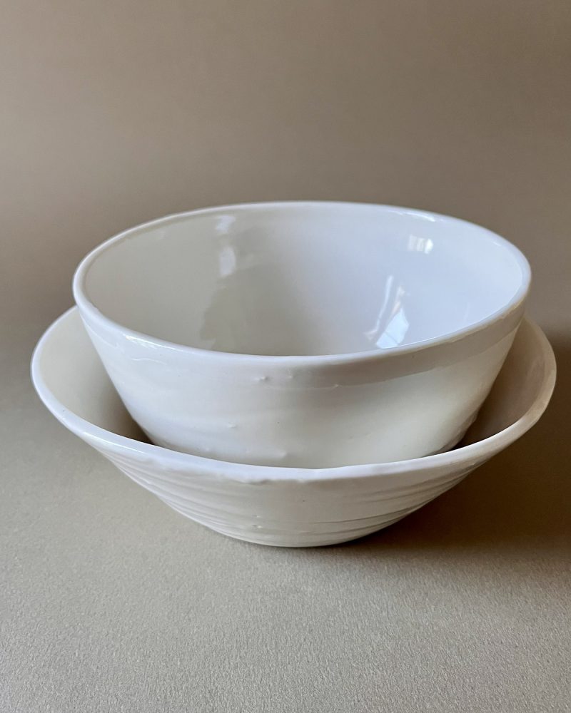Deux bols Purete en porcelaine blanche emboîtés, vue de face sur fond beige