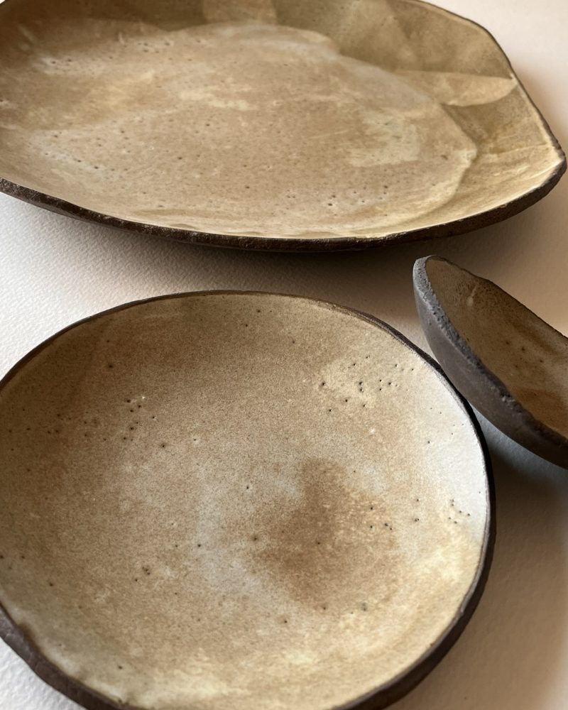 Assiettes et coupelle en grès brun à l'émail beige nuageux, formes libres, vues de dessus
