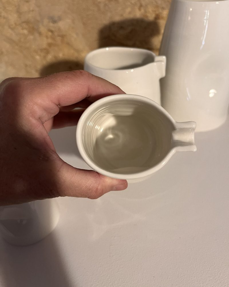 Saucière verseuse en porcelaine blanche tenue en main et vue de dessus, bec verseur et intérieur strié
