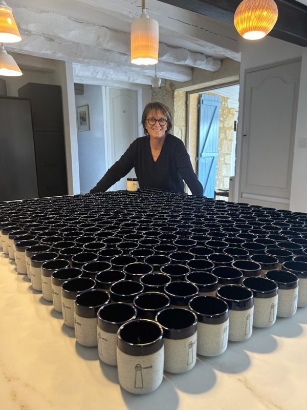 Agnès Guerinon souriante derrière une table couverte de 300 tasses en grès blanc et noir pour Qualrisk